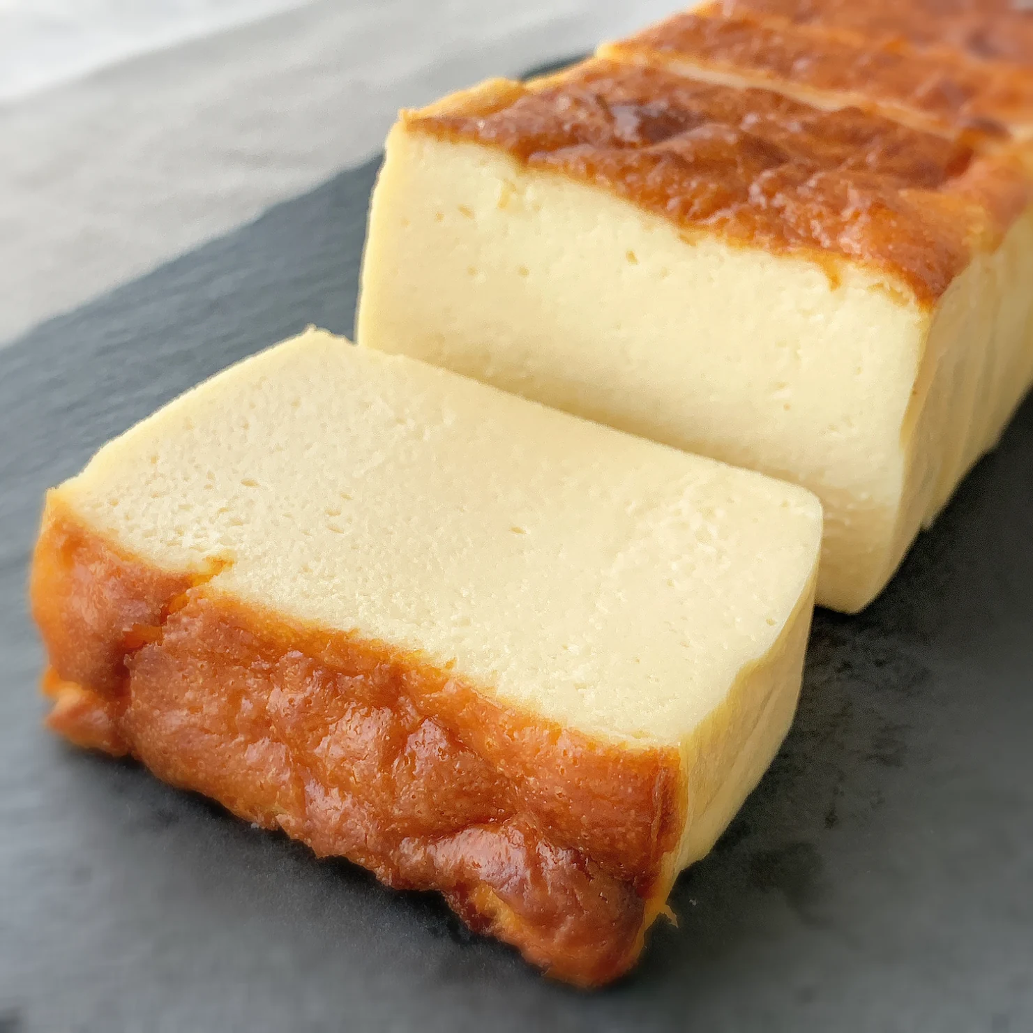 切り分けたチーズケーキと、焼き色のついたホールのチーズケーキ