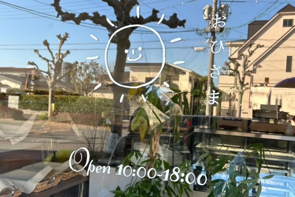 おひさまの文字と絵が描かれたお店の窓